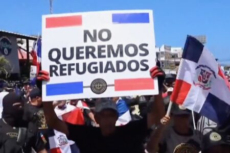 Man holds sign that reads, "We Don't Want Refugees" during the nationalist march in the Dominican Republic on March 30. Photo: screenshot